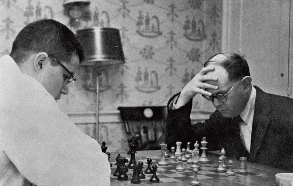 A black and white photo of two people playing chess.