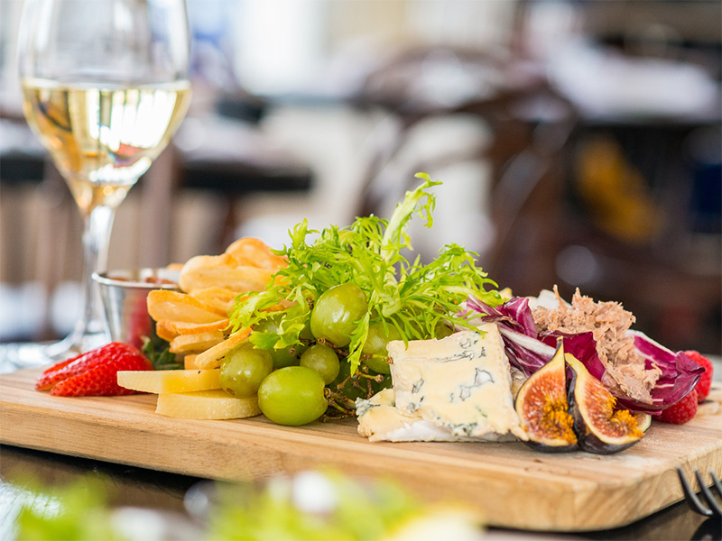 A tray with cheese, fruit and wine