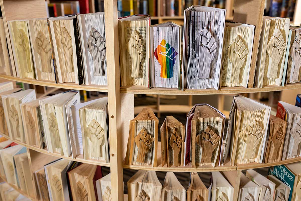Close up of books on a shelf; each book has a solidarity fist sculpted into it
