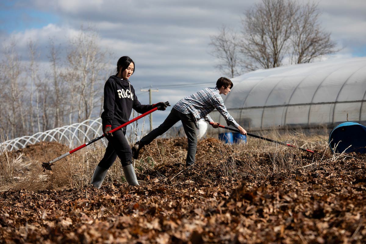 A student and a farm staff member raking