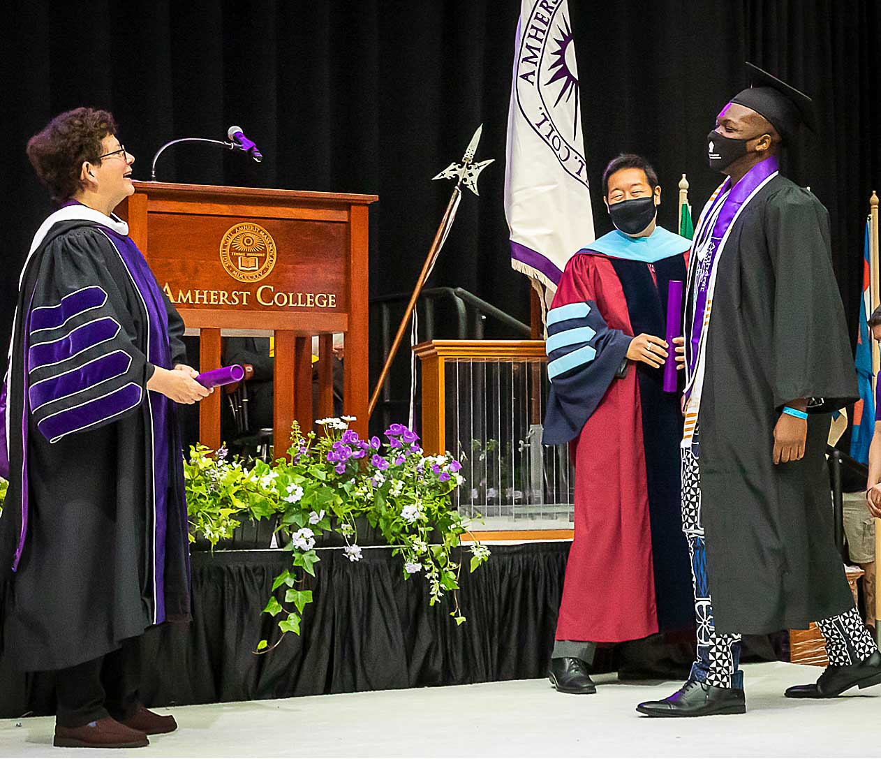 A graduate approaches President Martin to receive his degree