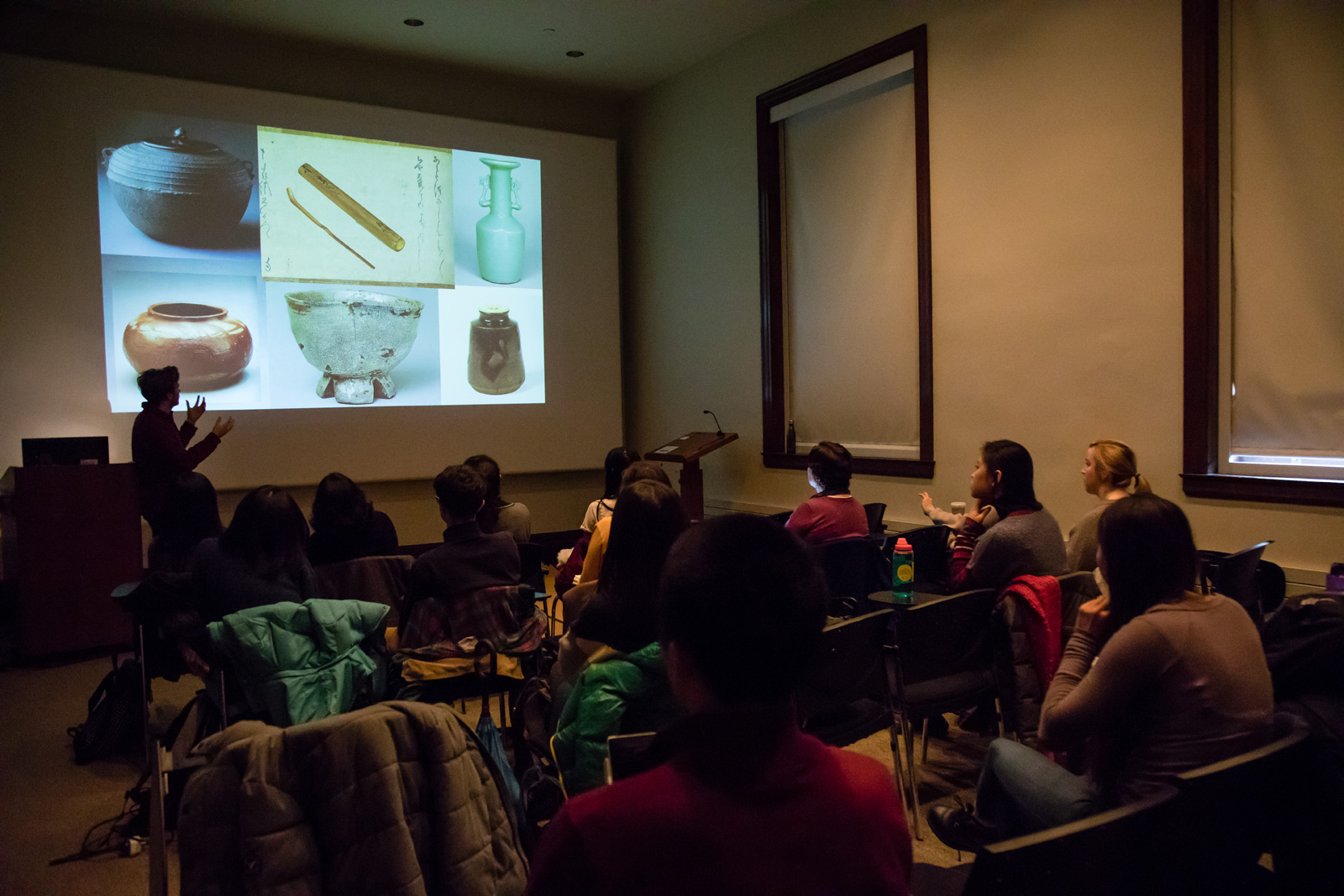 Students in a classroom discuss slideshow showing Japanese ceremonial ceramic bowls