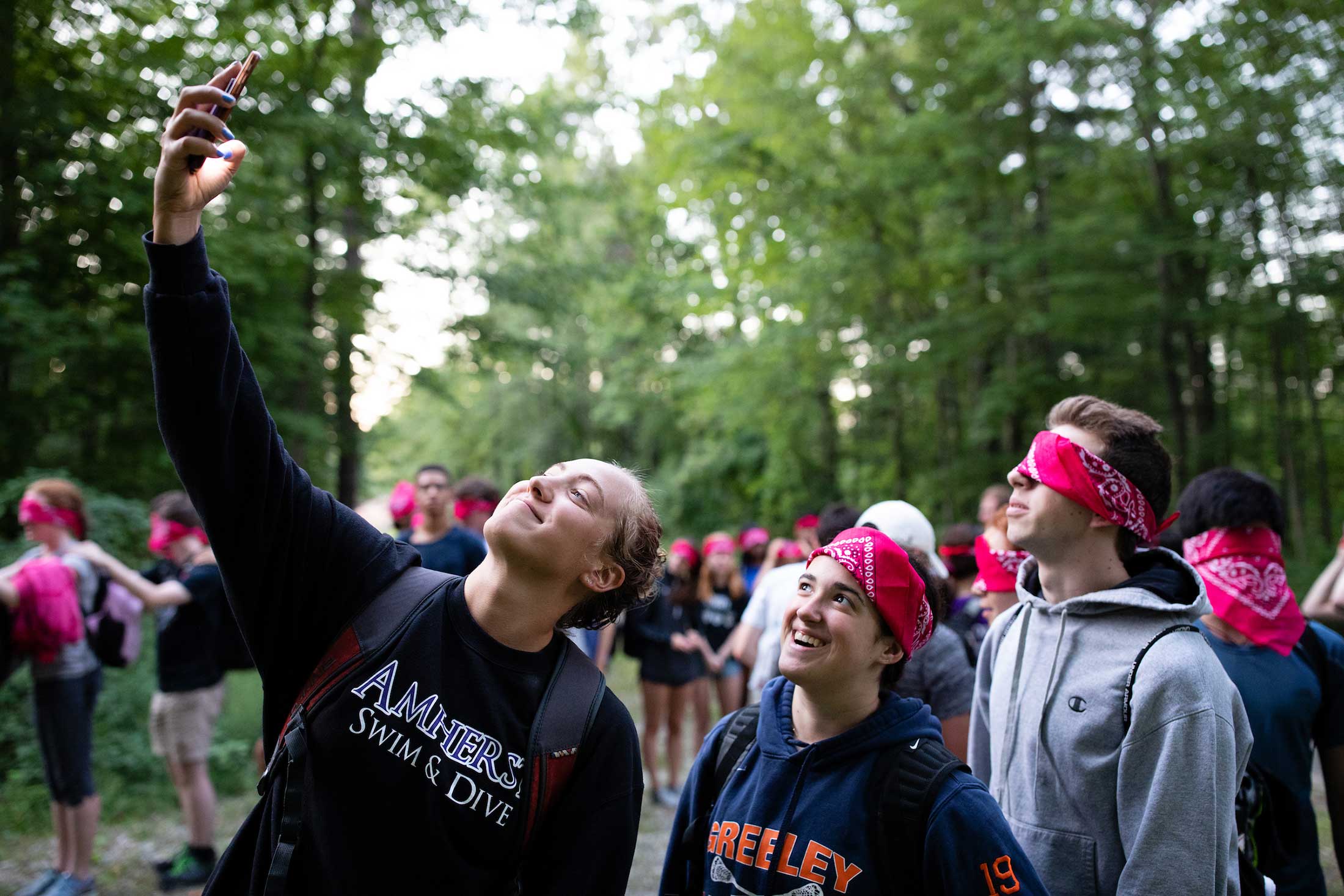Students, all wearing red bandanas on their heads, pose for a selfie during an orientation activity.