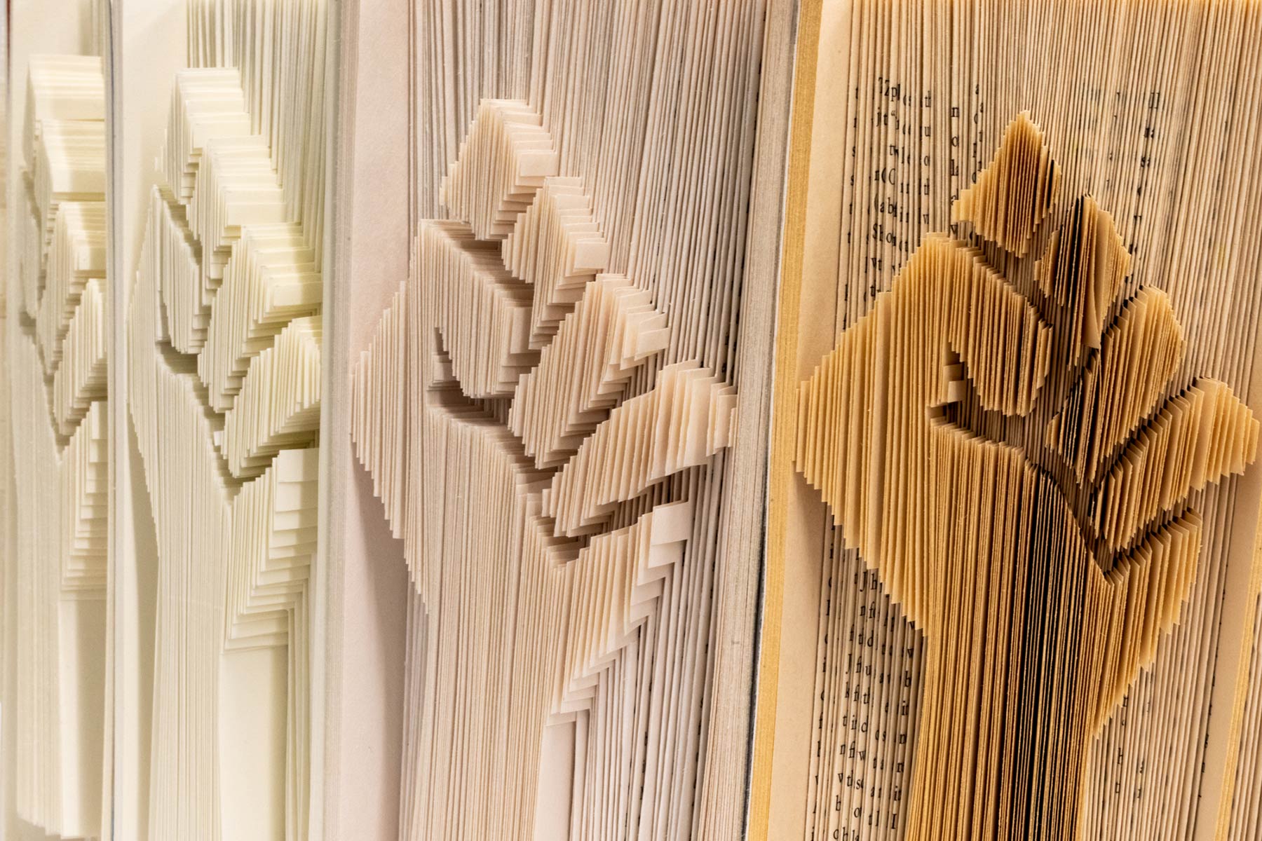 a close up of fine book sculpture showing a closed fist carved into the pages of the book