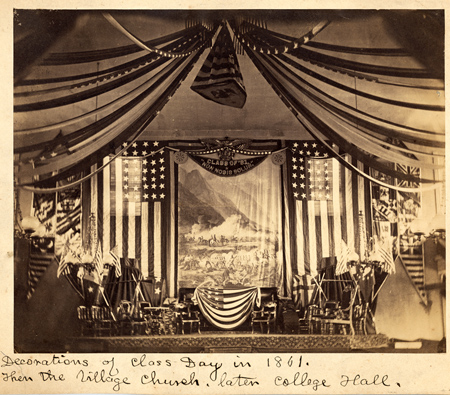 archival photo of class day in 1861 showing a stage decorated with American flags