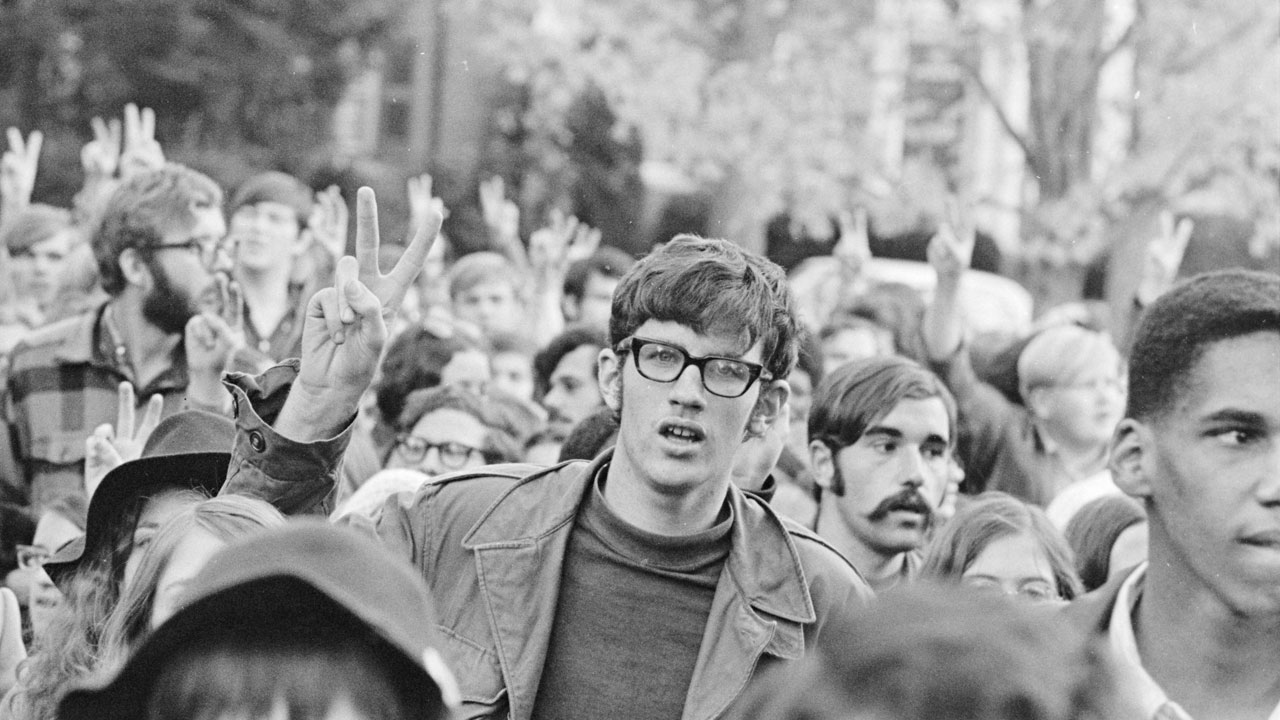 crowd of students marching and holding up their hands to make the peace sign in 1969