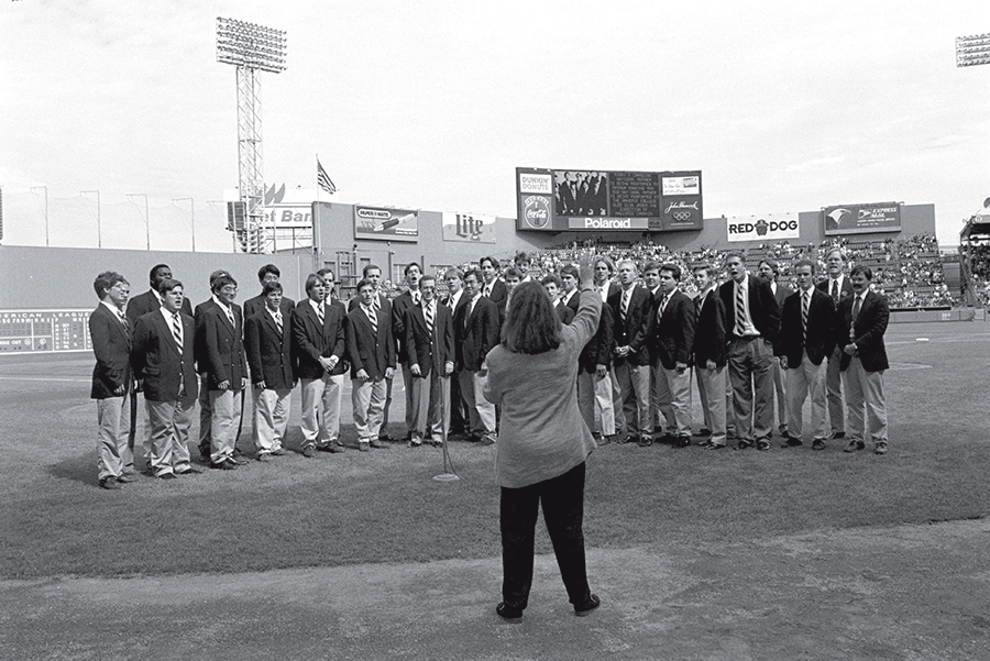 A black and white photo of a group of singers singing on the field of Fenway Park