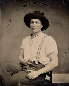 An old photo of a young man in suspenders and a hat
