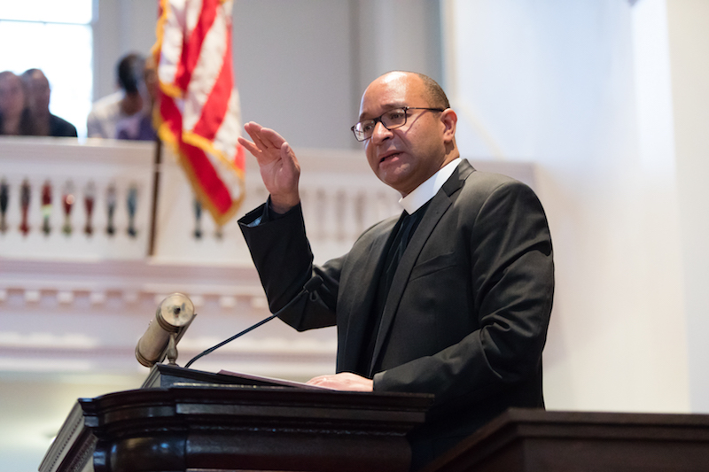 Rev. Phillip Jackson ’85 at the podium in Johnson Chapel, with the American flag in the background