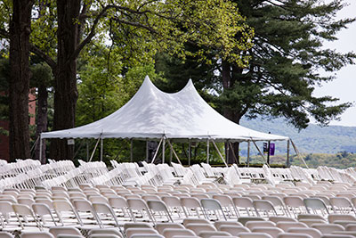A white tent and rows upon rows of white chairs set up outside