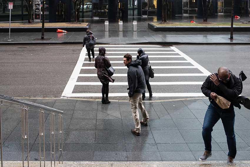 Amherst students crossing a street in Boston on an extremely rainy and windy day