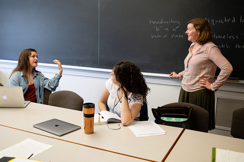 Sara Brenneis speaking to two female students in a seminar class