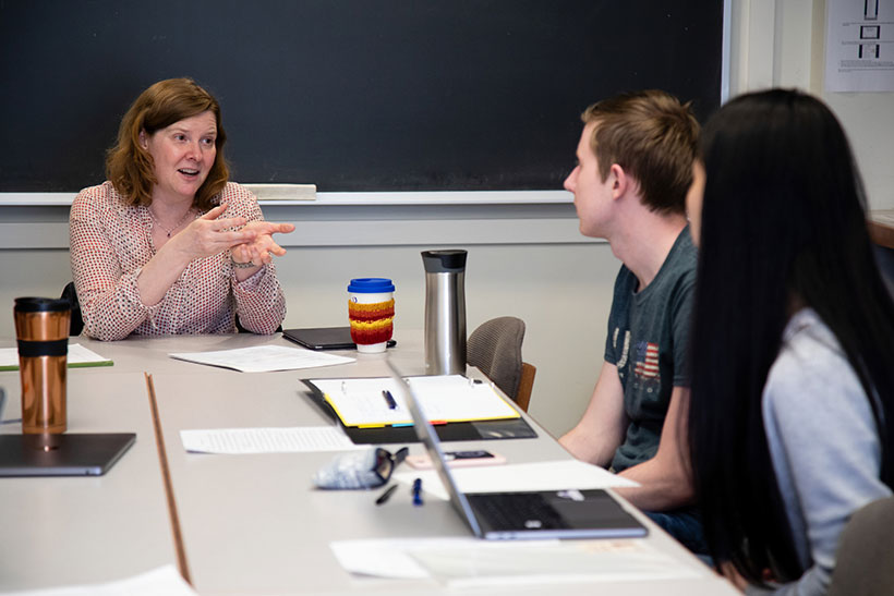 Professor Sara Brenneis seated at a seminar table with two students