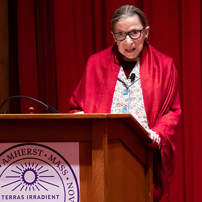 Justice Ruth Bader Ginsburg stands at a podium