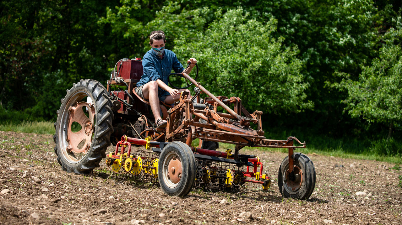a farm staffer plows a field with the electric tractor
