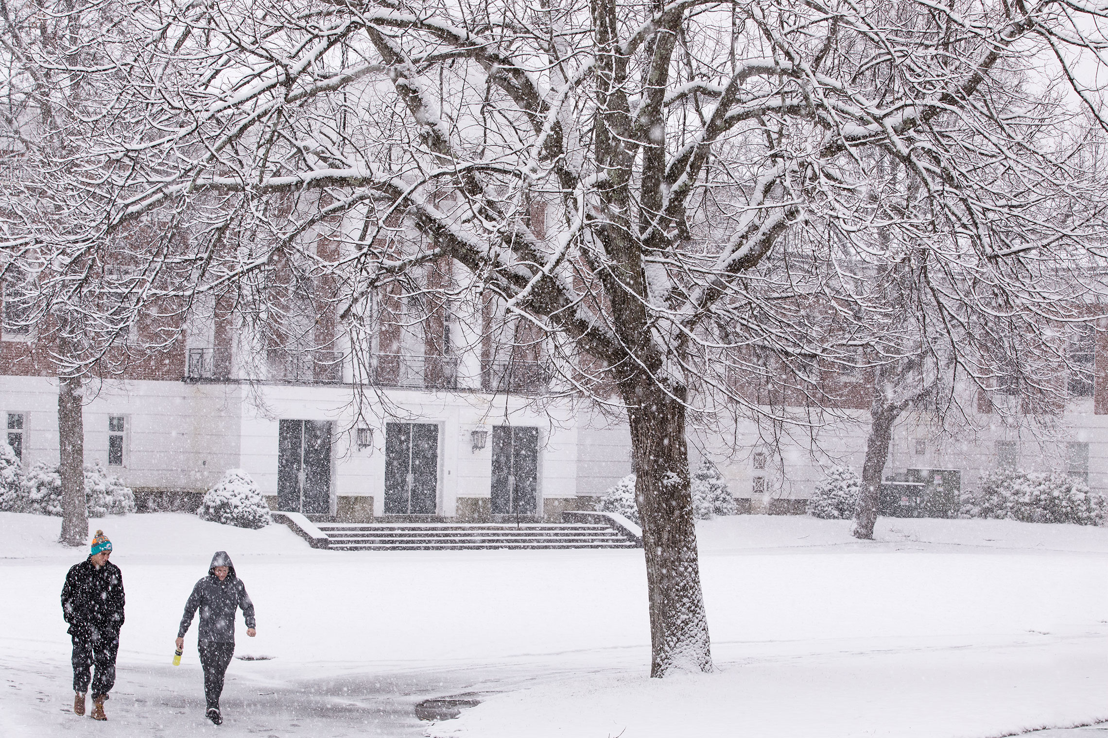 Student walking across campus during the first snowfall of 2017.