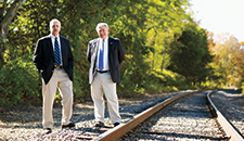 George Betke ’59 and Mike Smith ’68 standing beside railroad tracks