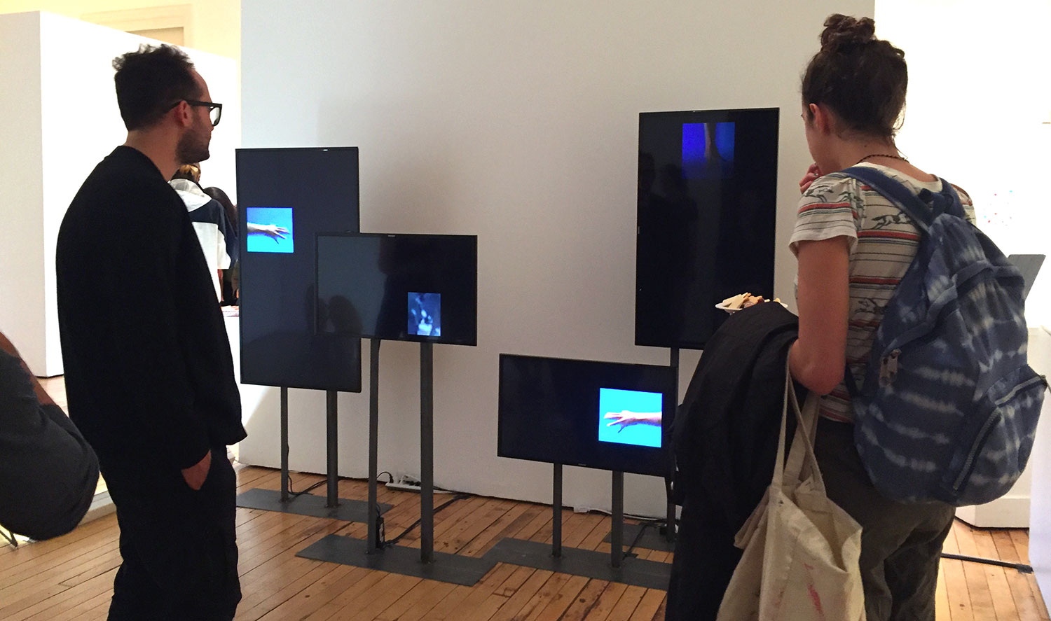 Installation view of TV monitors and two people looking at them