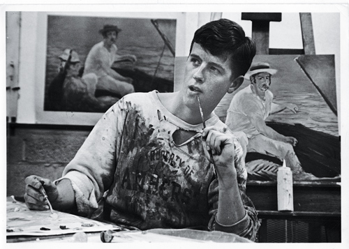 Student with paint on shirt in front of canvas