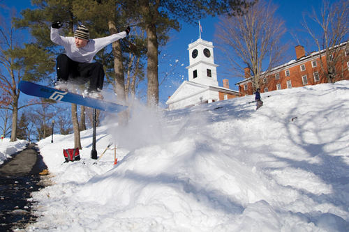 Student snowboarder airborne in front of Johnson Chapel