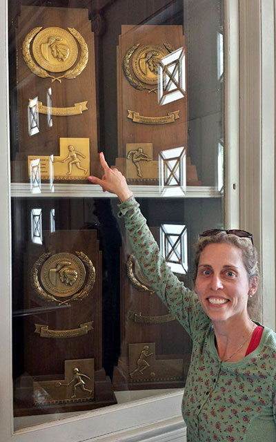A woman points at a trophy in  a case