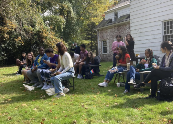 A group of students sitting in lawn chairs in a backyard