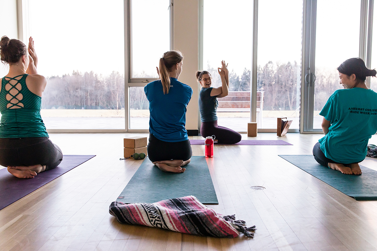 Students doing yoga in front of a window overlooking campus