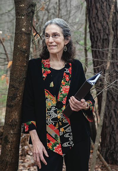 A photo of a woman in the woods holding a book