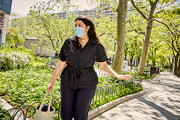 A woman in a face mask wearing a black medical uniform in a city park