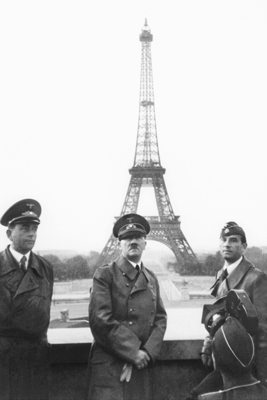 Hitler and several other men posing in front of the Eiffel Tower
