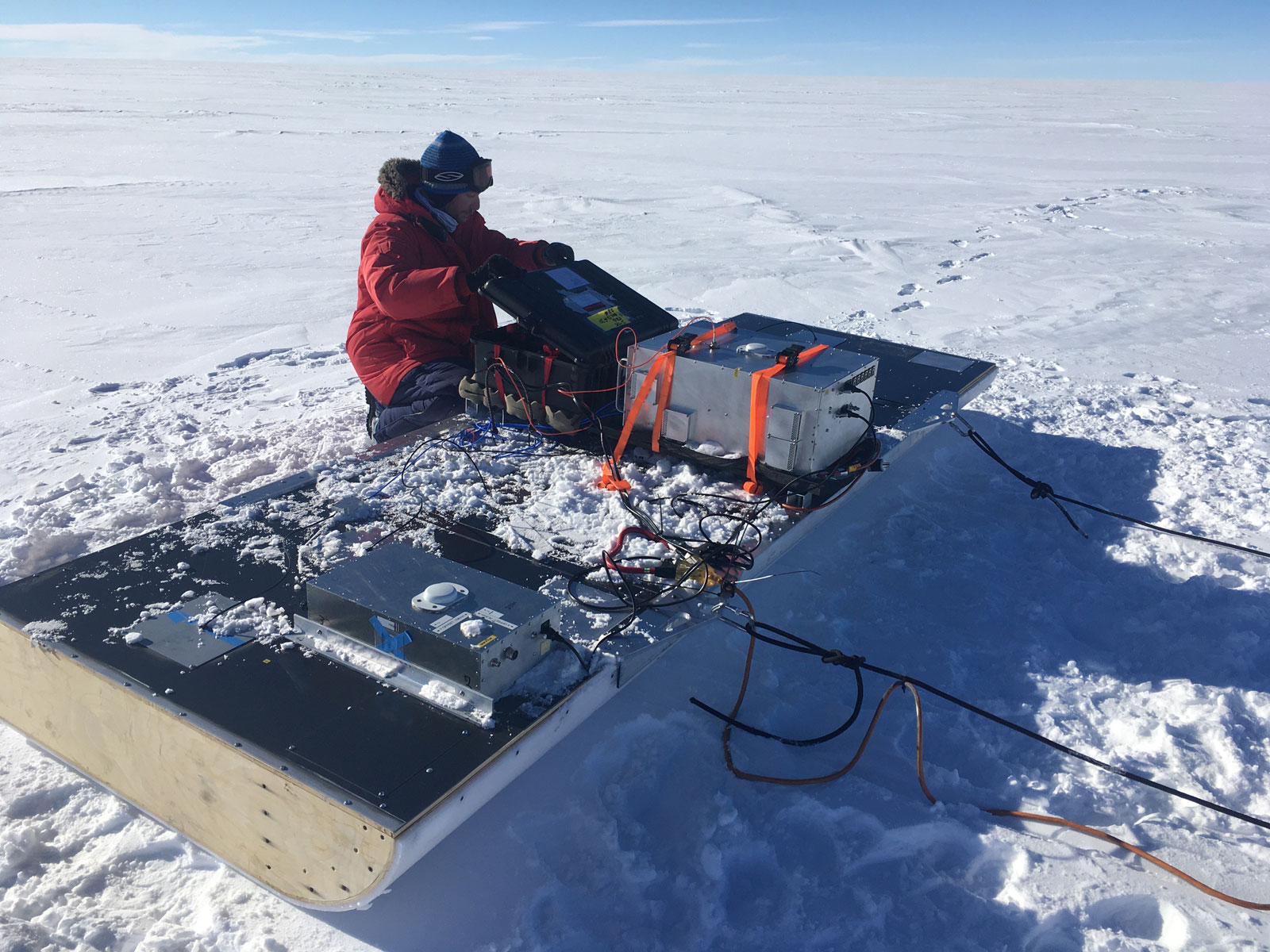 Professor Holschuh loads scientific equipment onto a sled on the snow in Antarctica