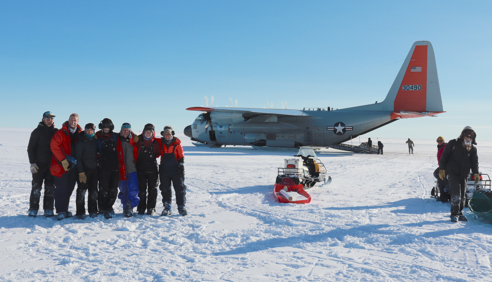 a group of people poses together near a plane before leaving Antarctica