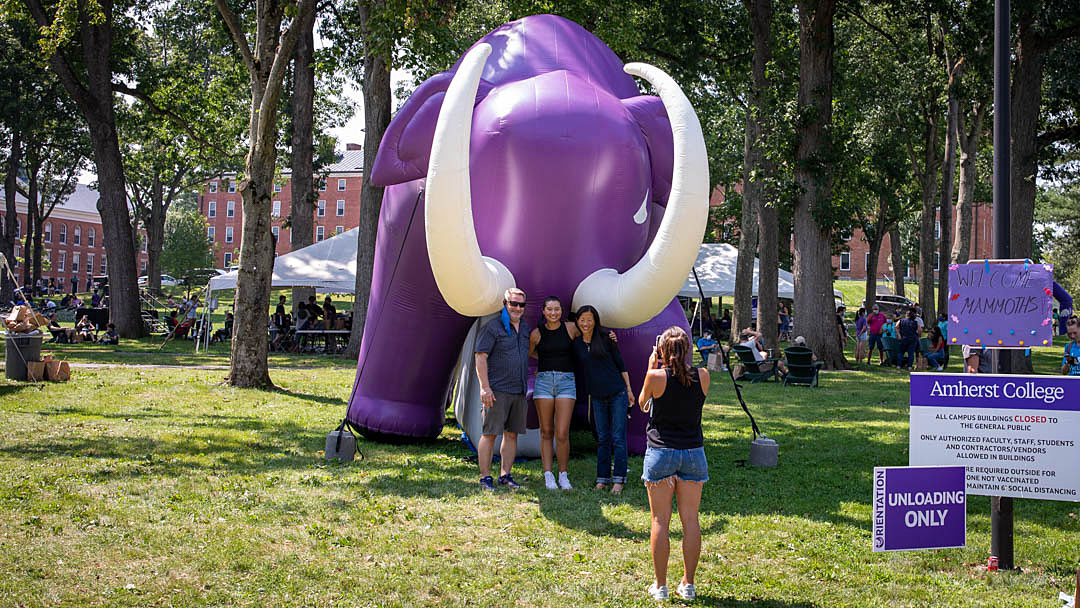 A family poses by an large inflatable purple mammoth at Amherst College