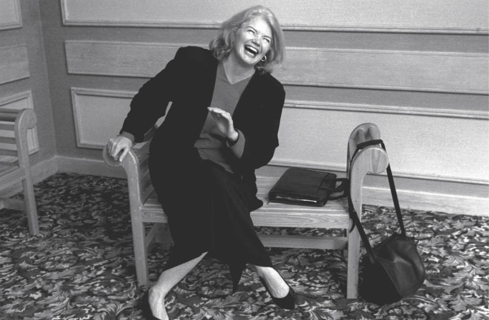 A black and white photo of a woman sitting and laughing
