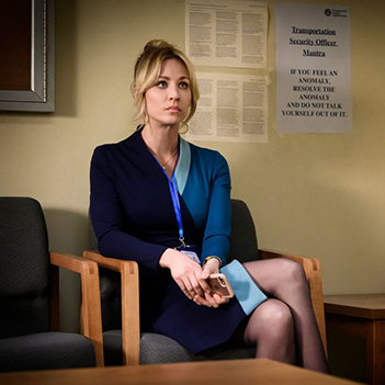 A photo of a young woman in a blue dress sitting in a waiting room