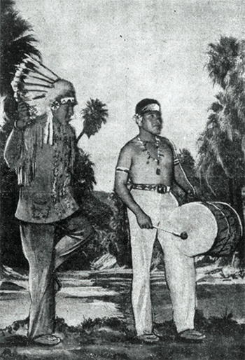 A black and white movie still of two people dressed as stereotypical Native Americans