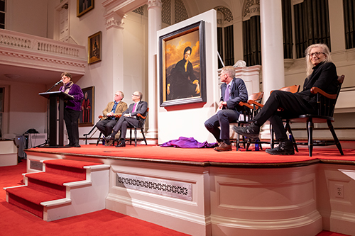 People on teh stage of Johnson Chapel revealing a large painting