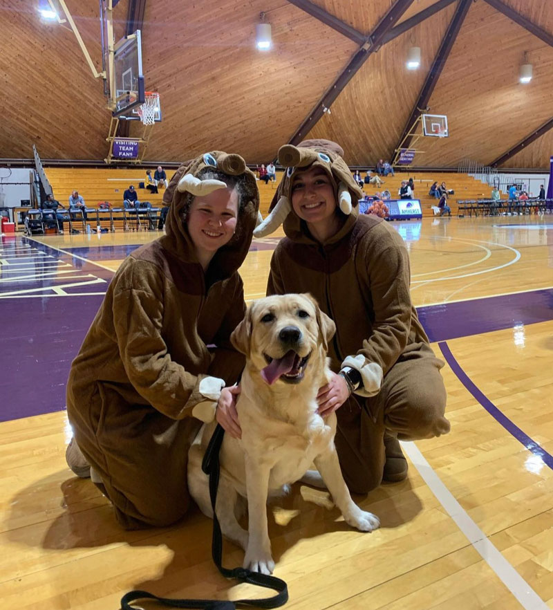 Moose the comfort dog with two students wearing mammoth costumes