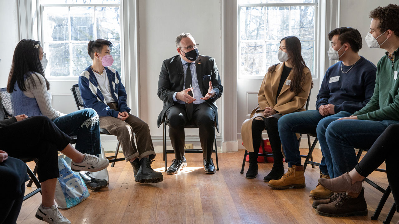 Miguel Cardona talks with students seated in a circle in the Emily Dickinson Museum parlor