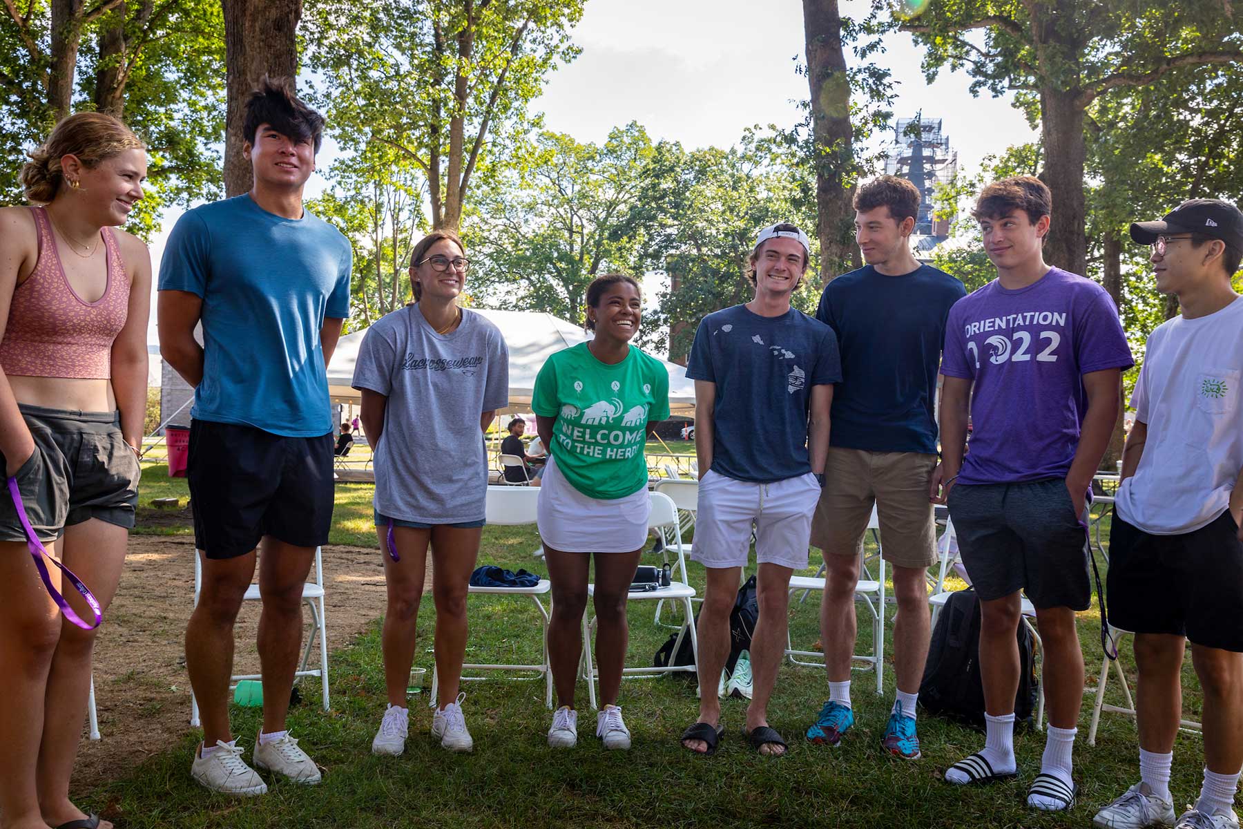 A group of students pose together in a semi-circle on the academic quad.