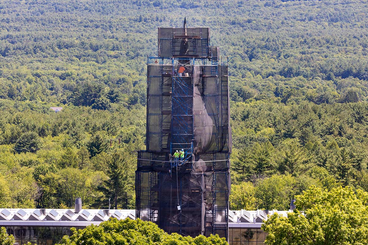 Three workers working on renovations to Stearns Steeple on a summer day at Amherst College