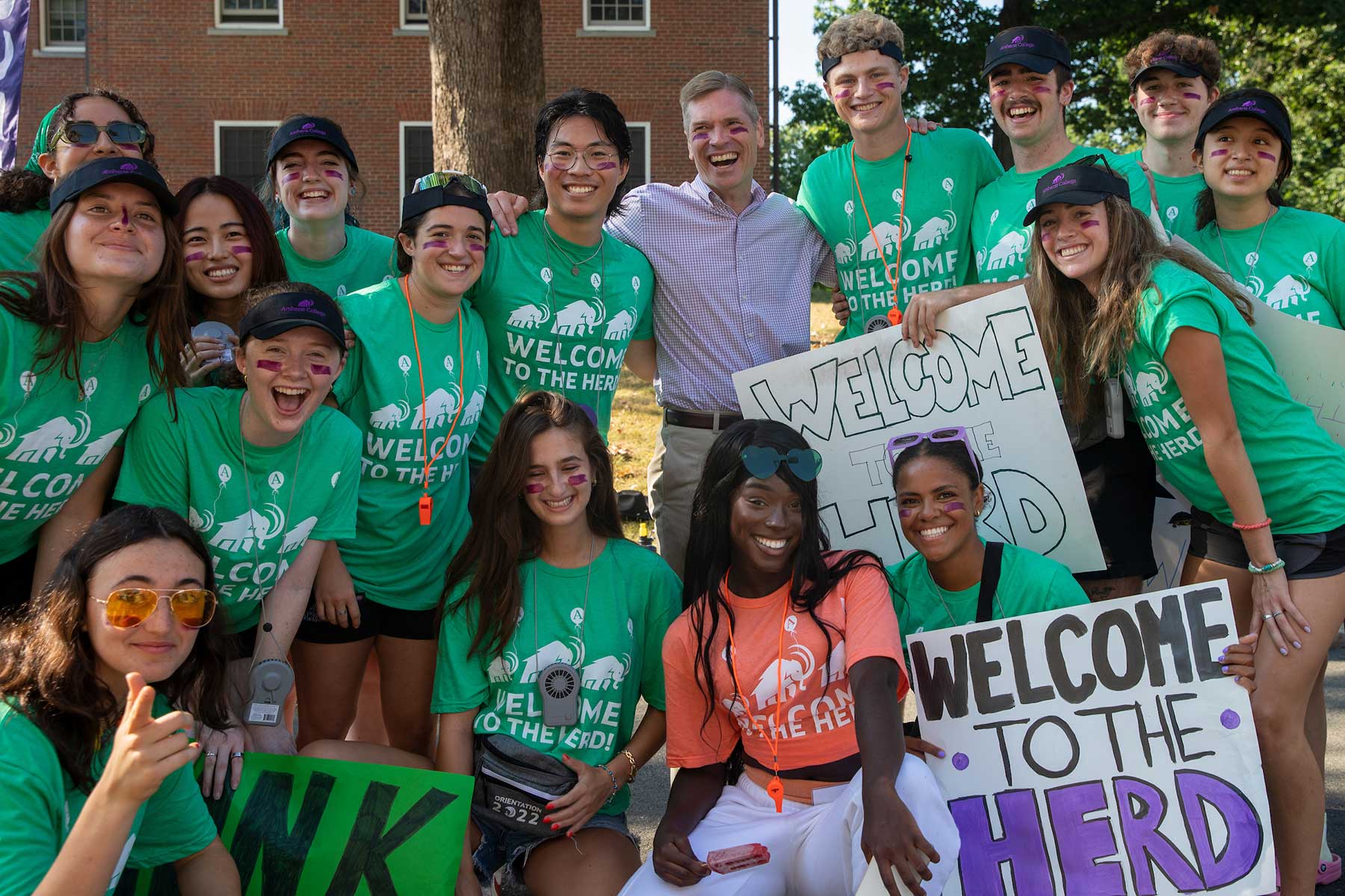 A large group of students in green matching tshirts hold up Welcome to the Herd signs.