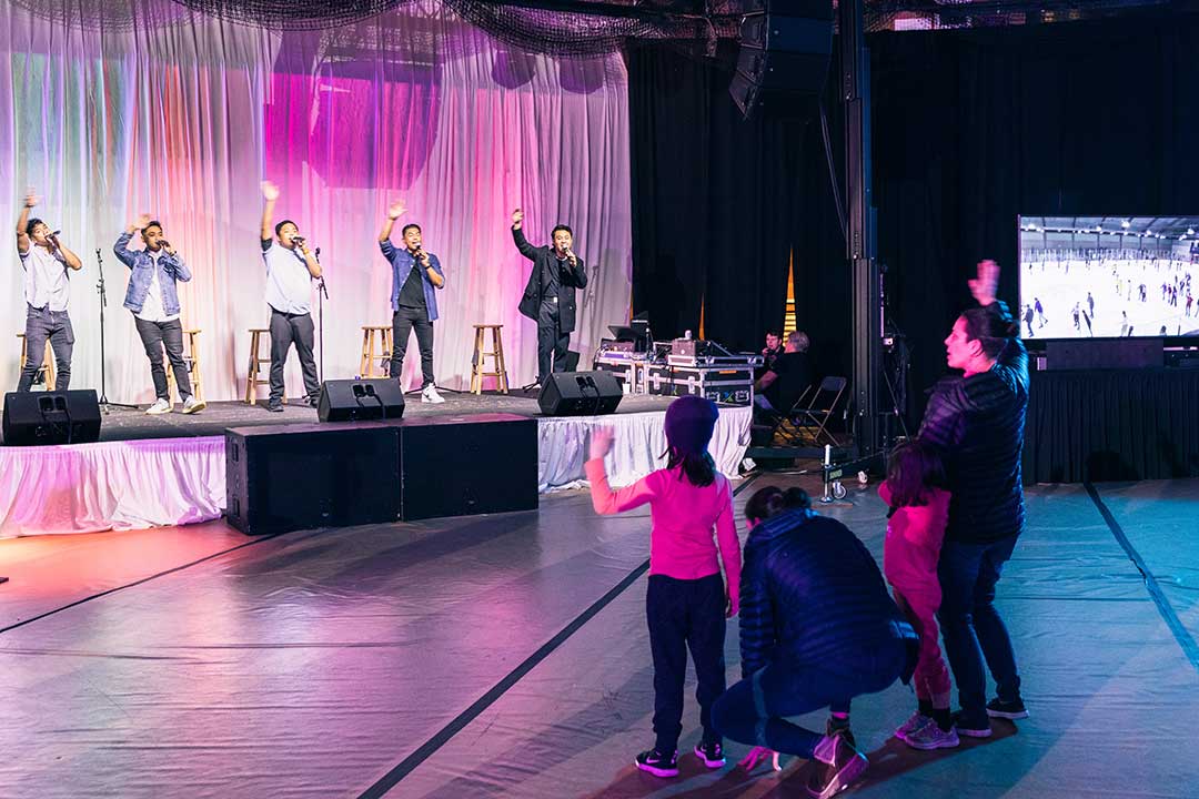 Audience members waves to the band performing on a stage.