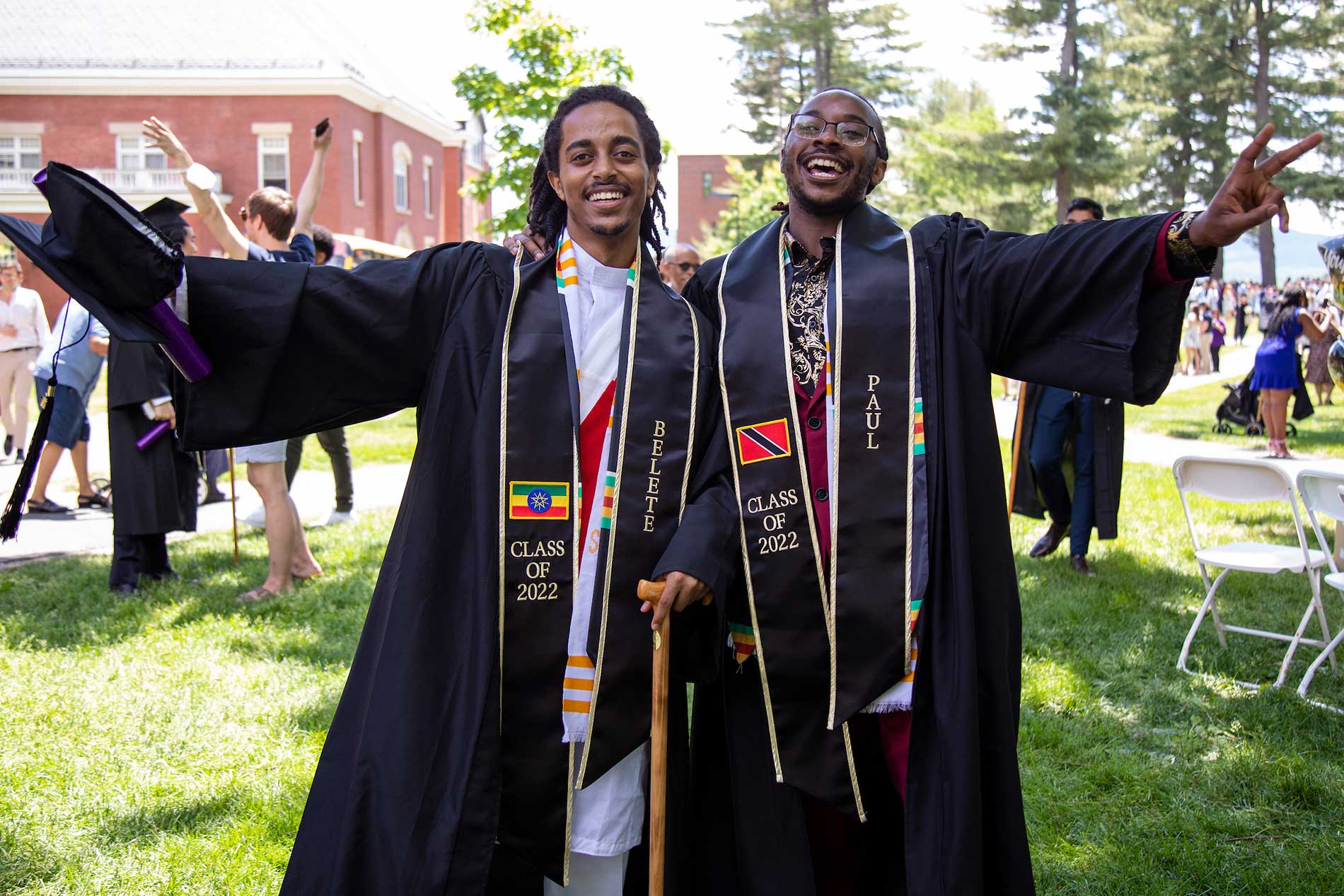 Two young black men pose together, their arms outstretched in celebration.