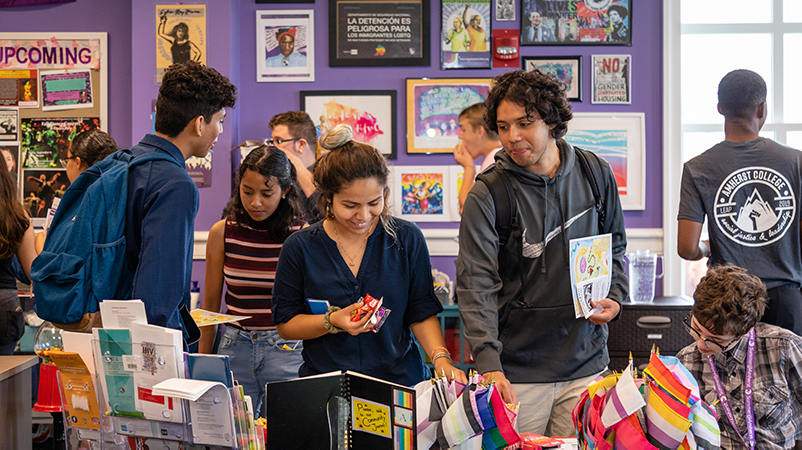 A group of students looking through a table of brightly colored flags and books