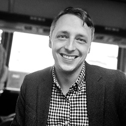 A black and white photo of a man in a suit with now tie