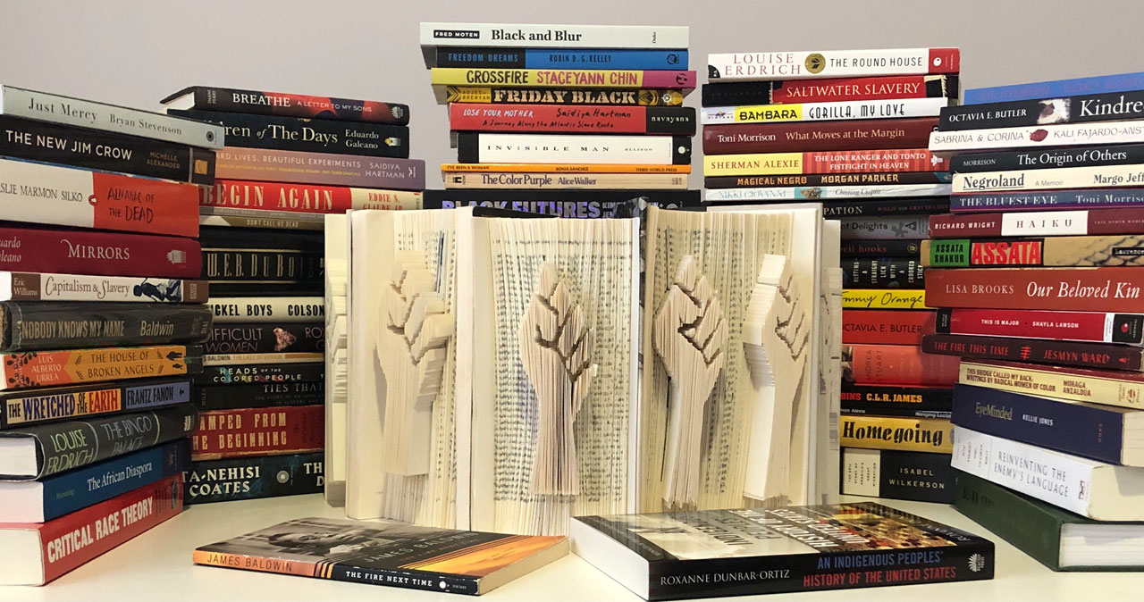 stacks of books and a book with a raised fist sculpted into the pages