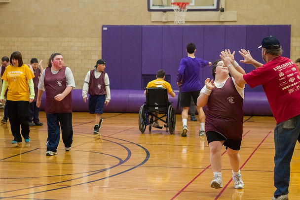 Special Olympics athletes, a coach and an Amherst College student on a basketball court in Alumni Gymnasium