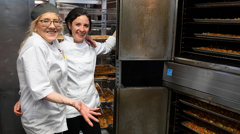 Two women in front of a large industrial oven