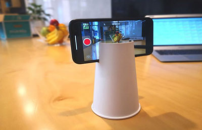 A disposable cup being used as a tripod to hold a cellphone